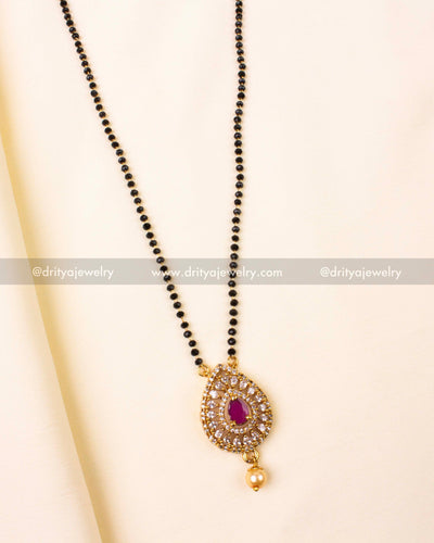 Red gemstone pendant surrounded by shimmering stones on black beads chain.