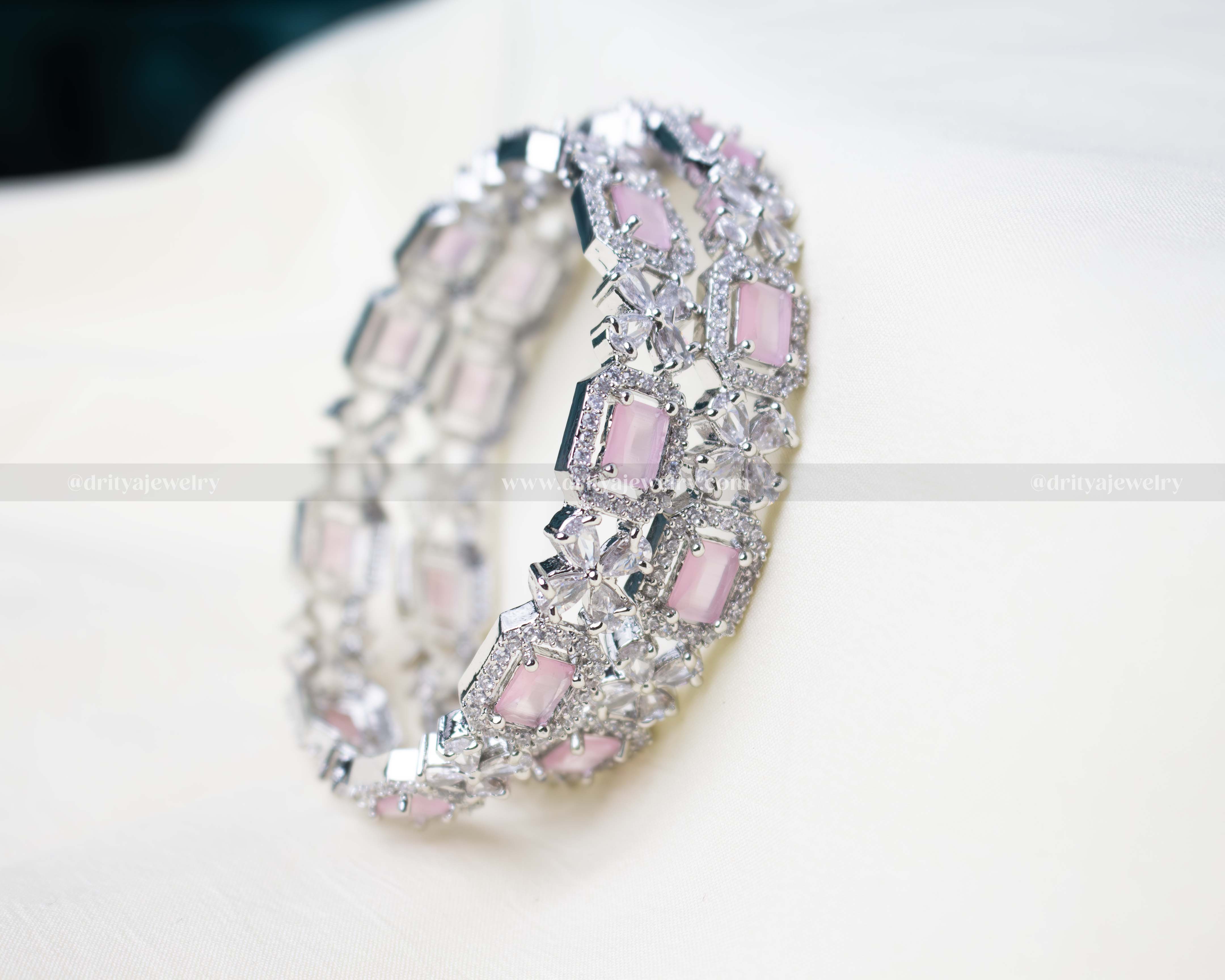 Pair of zircon bangles featuring blush pink gemstones and American Diamond embellishments in a silver-tone finish.