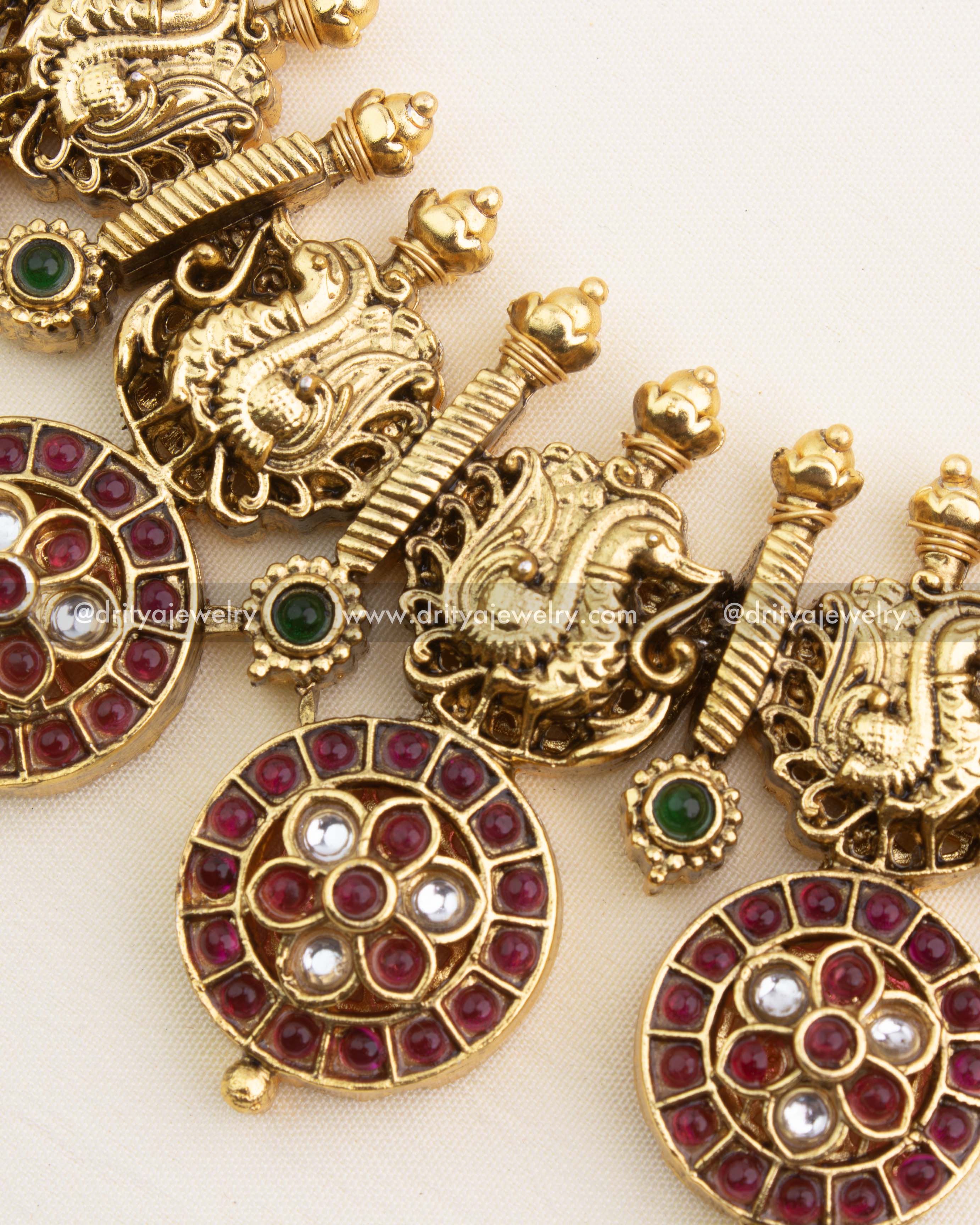 Close-up of ruby bottu discs, white CZ stones, green accents, and antique gold detailing.
