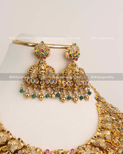 Traditional temple jhumka earrings with emerald green stone detailing and pearl bead layers.