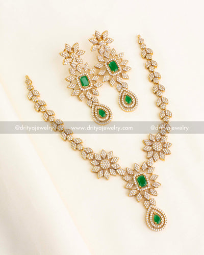 Gold-tone floral necklace set with green stones and cubic zirconia embellishments.