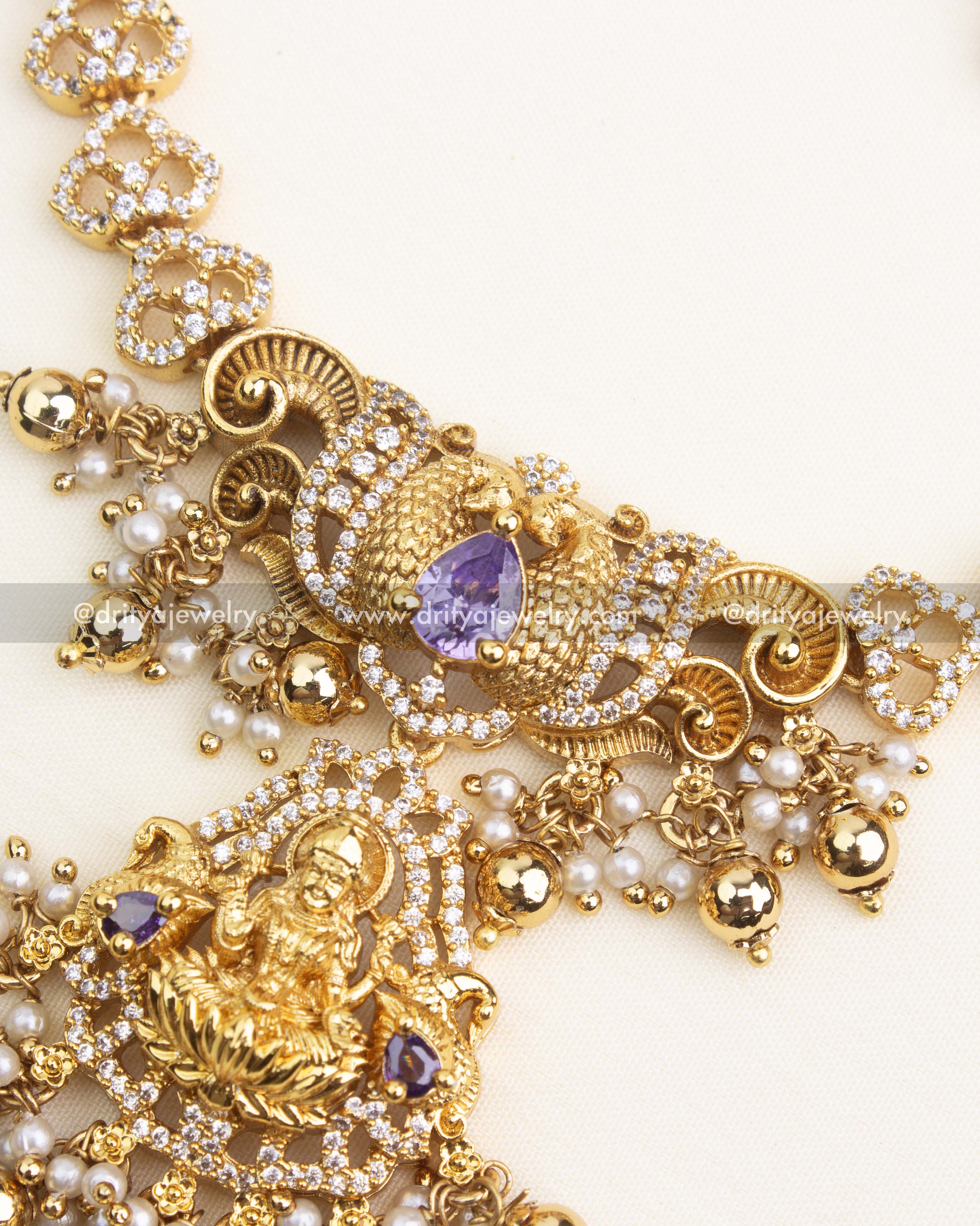 Close-up of Lakshmi pendant with CZ detailing, purple gemstone, and pearl-gold droplet clusters