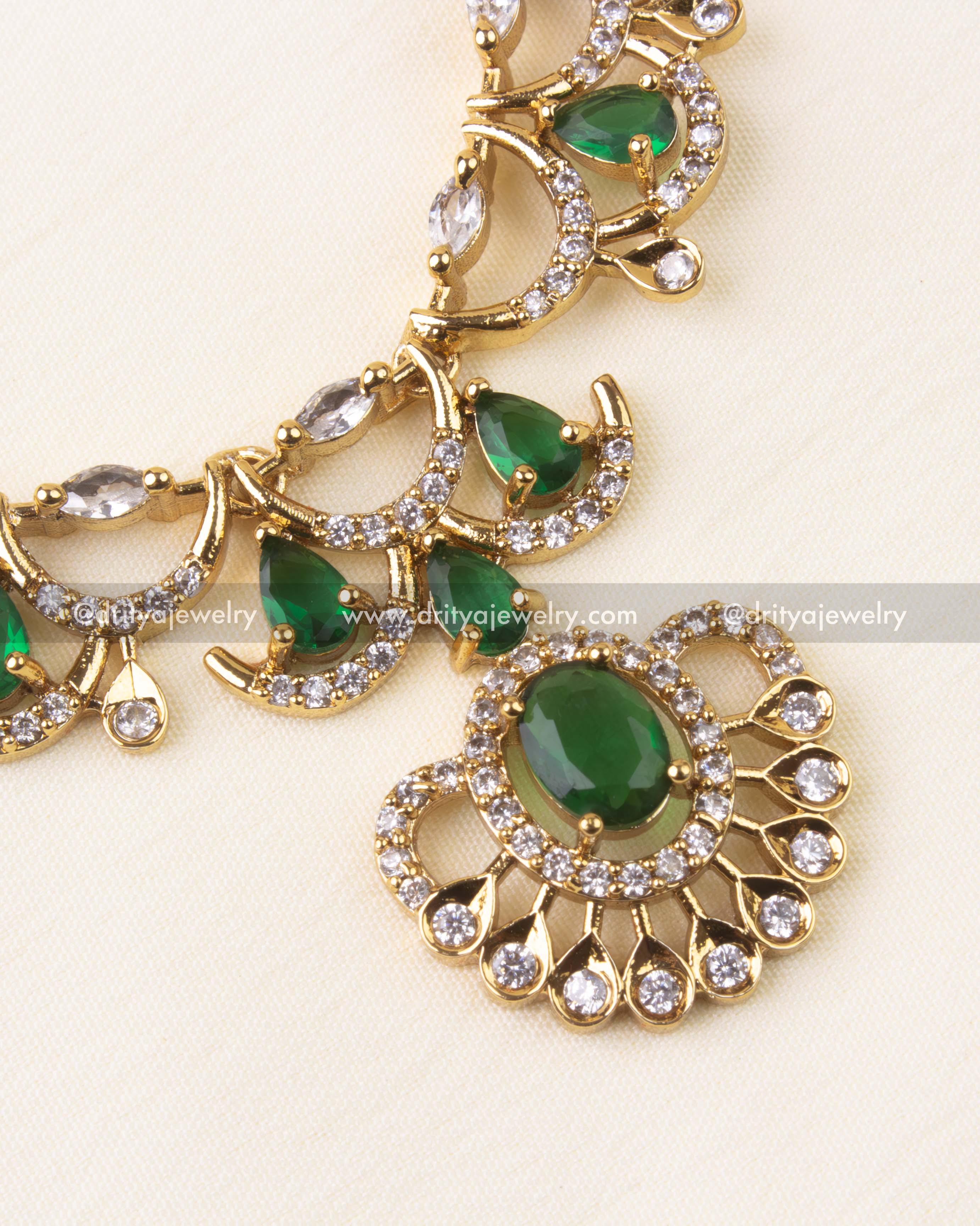 Magnified view of the central pendant with teardrop emerald surrounded by white CZs.