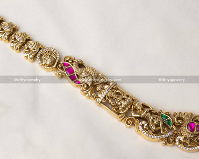 Close-up of a deity pendant with pearls, kemp stones, and intricate nakshi work.