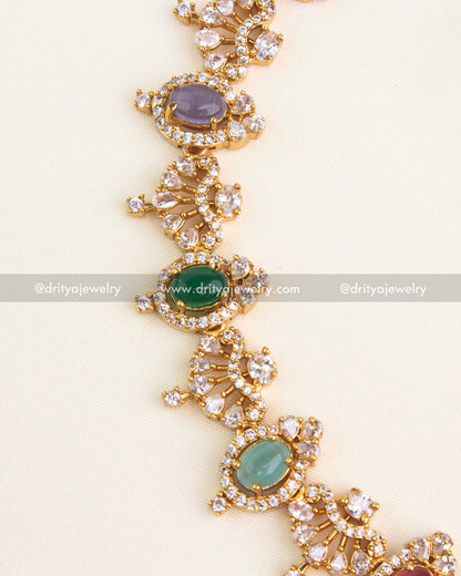 Detailed view showing oval multicolor cabochons, pear-shaped CZ fans, and pavé halo setting on a gold short necklace.