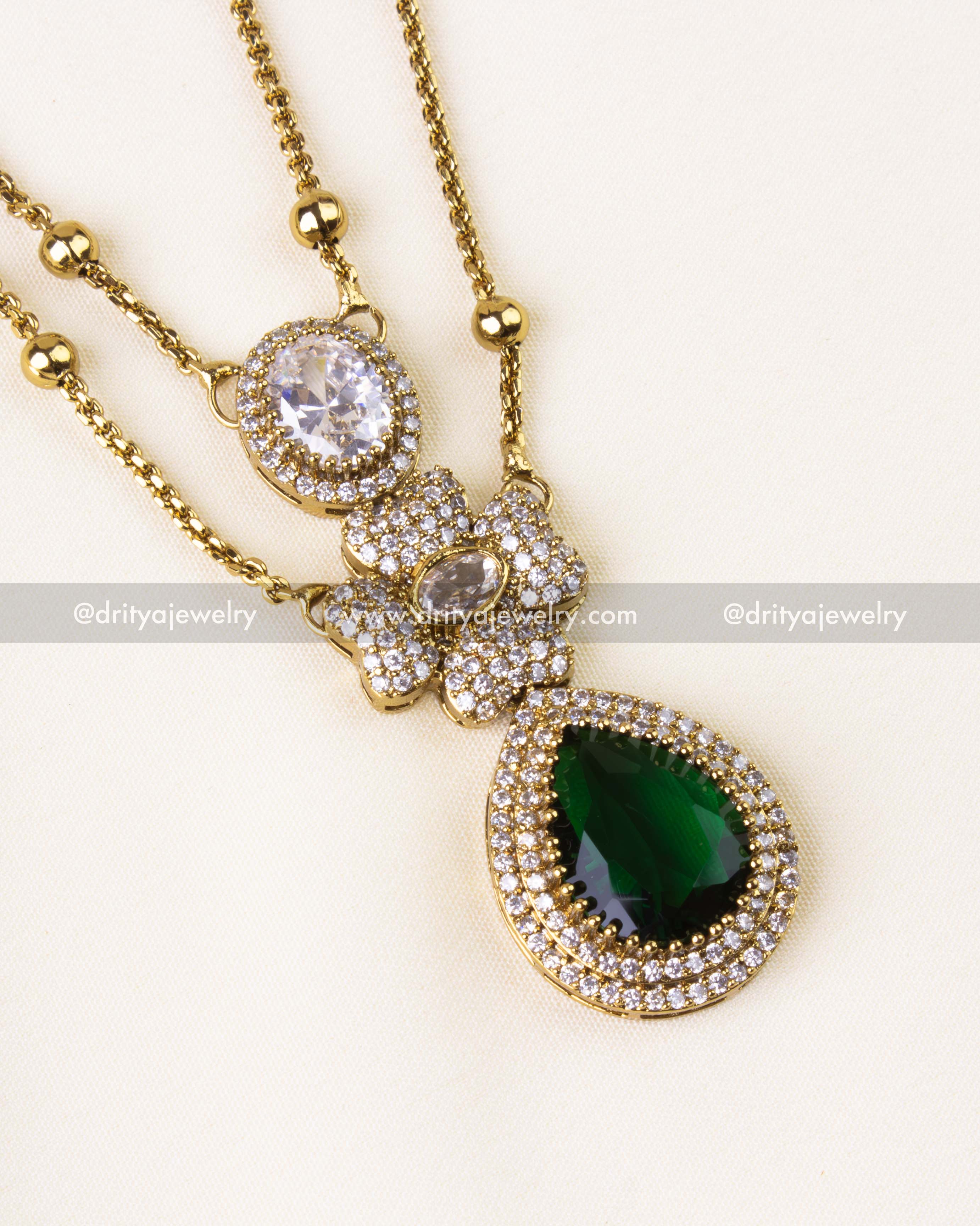 Detailed view of the layered pendant featuring emerald green teardrop stone and American diamonds