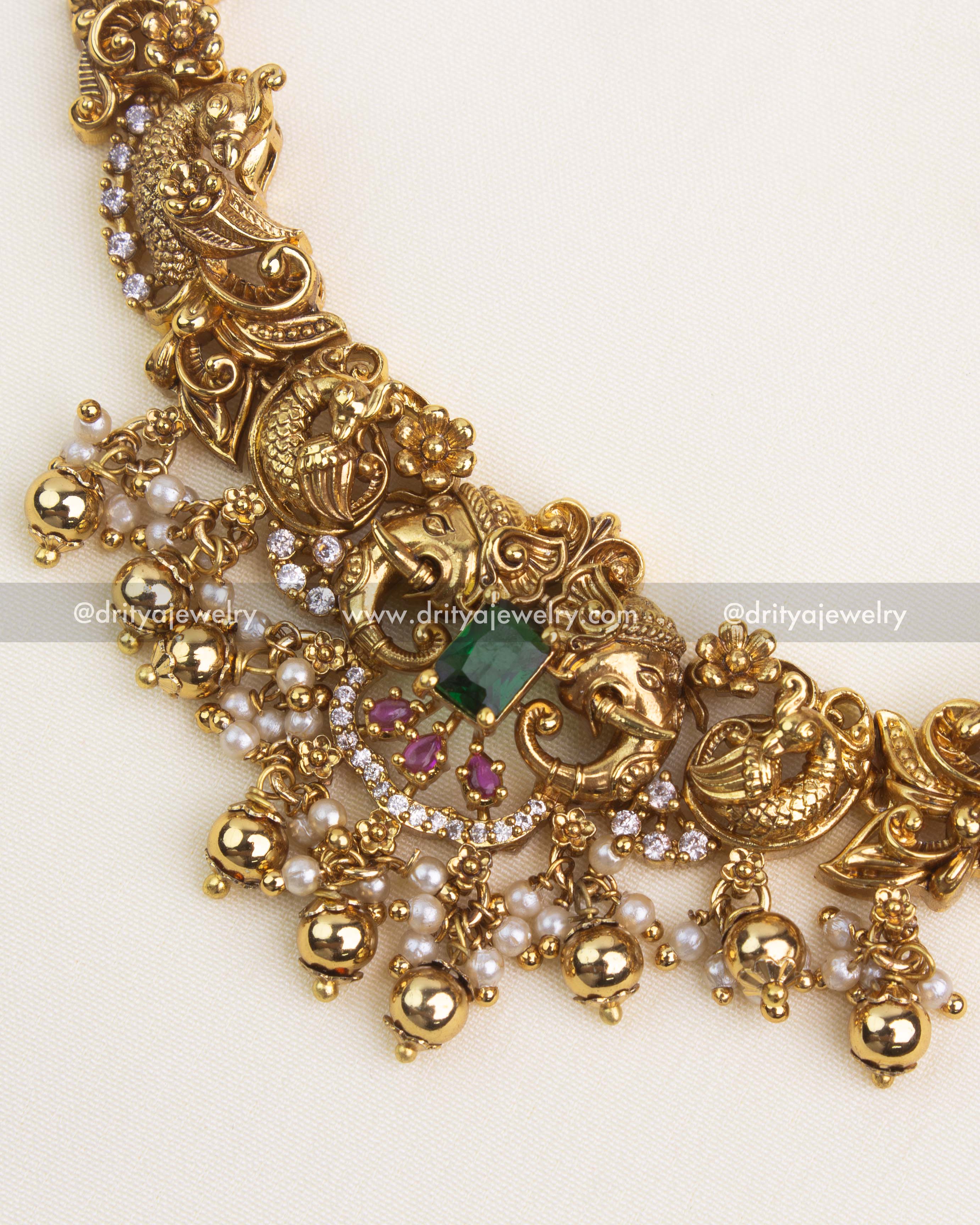 Handcrafted nakshi carvings featuring peacock motifs, embedded emerald green and ruby stones with pearl hangings.