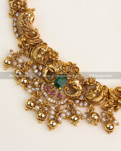 Handcrafted nakshi carvings featuring peacock motifs, embedded emerald green and ruby stones with pearl hangings.