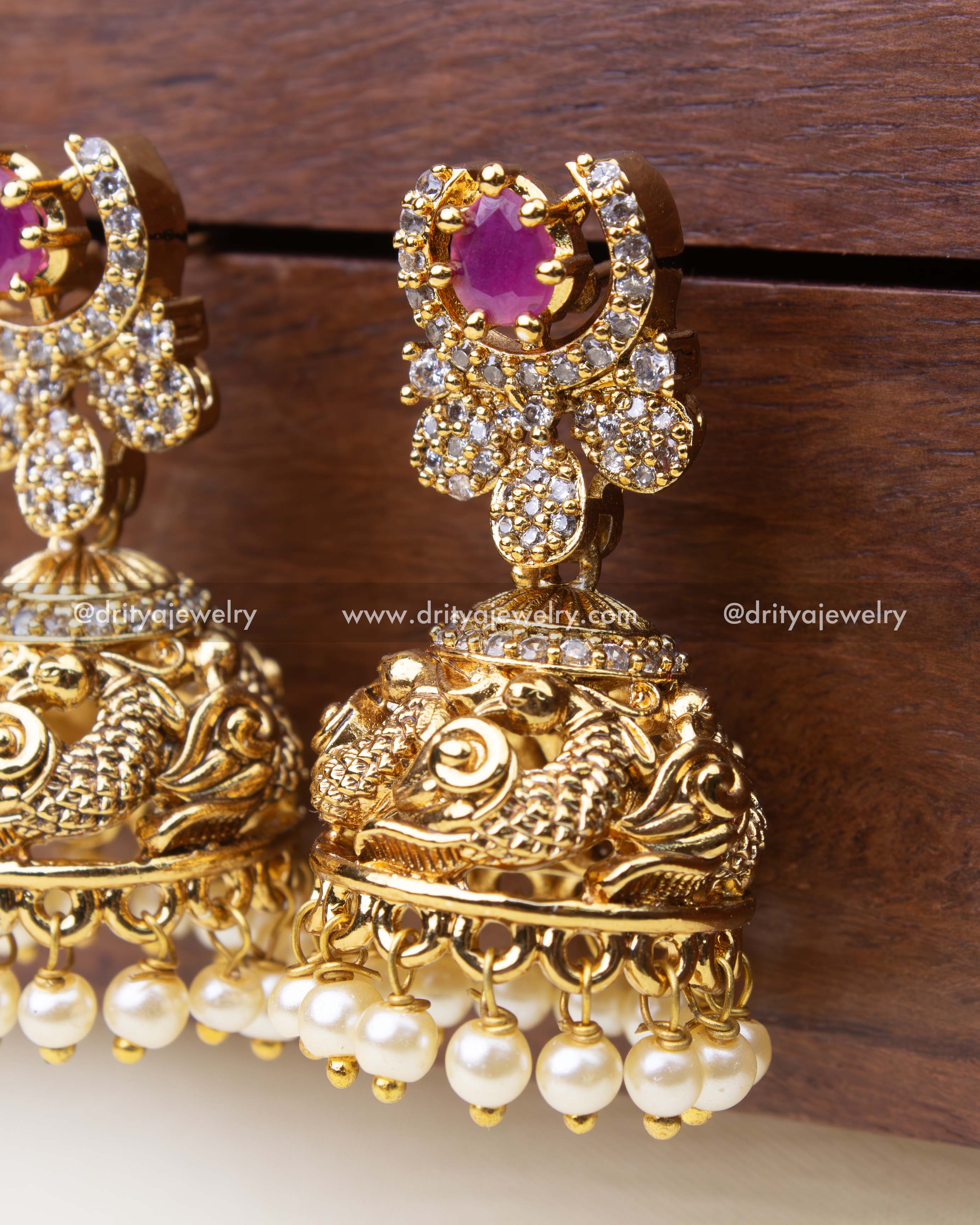 Detailed view of pink stone Antique jhumkas featuring peacock carving and pearl danglers.