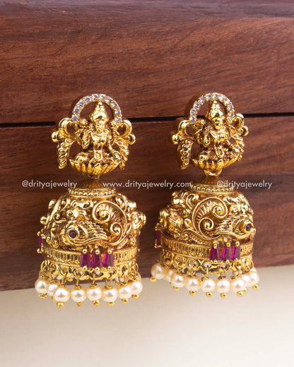Antique gold jhumka with red rectangular stones, Lakshmi idol, and pearl clusters on the base.