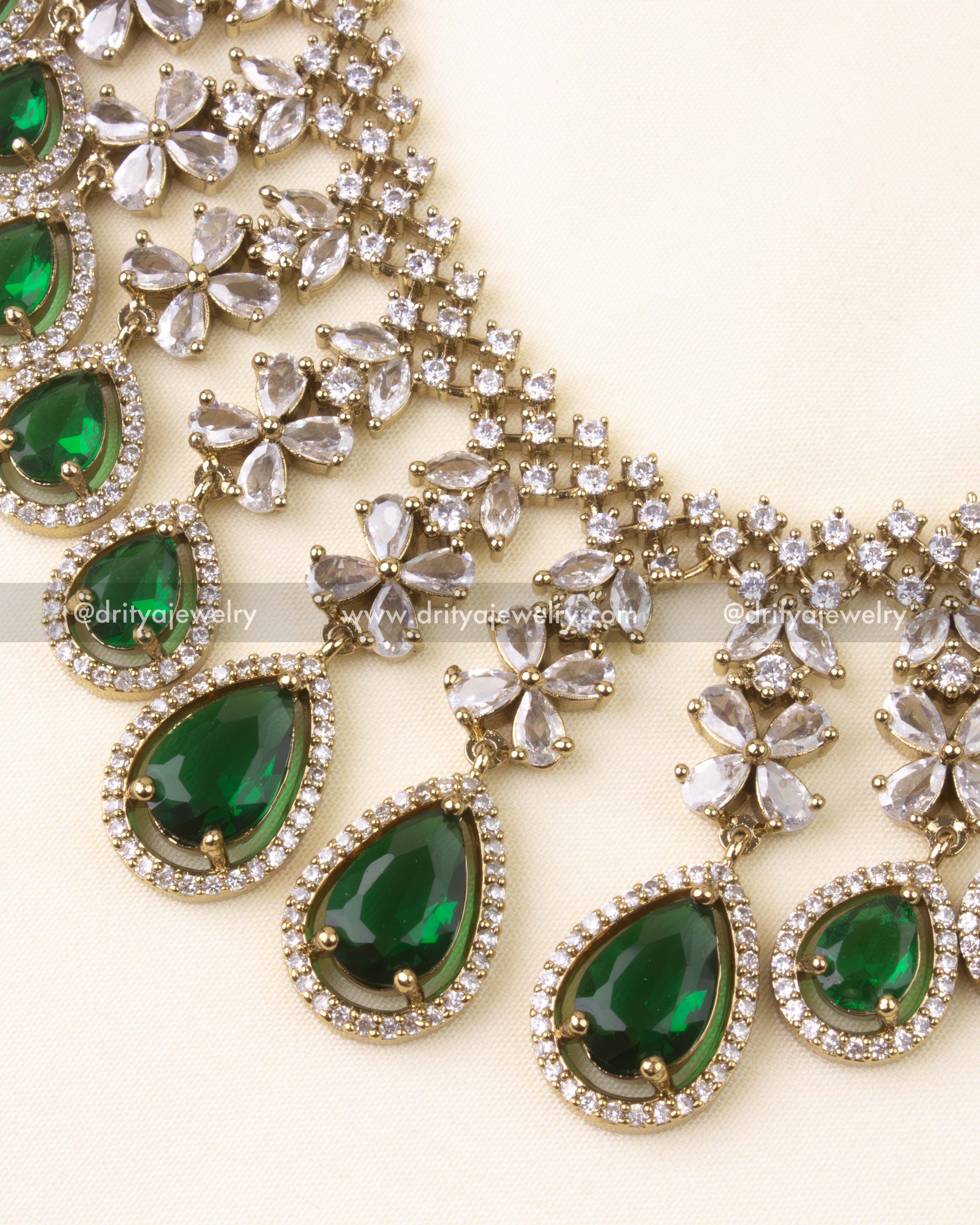 Detailed close-up of necklace showing emerald green teardrop stones with American Diamonds
