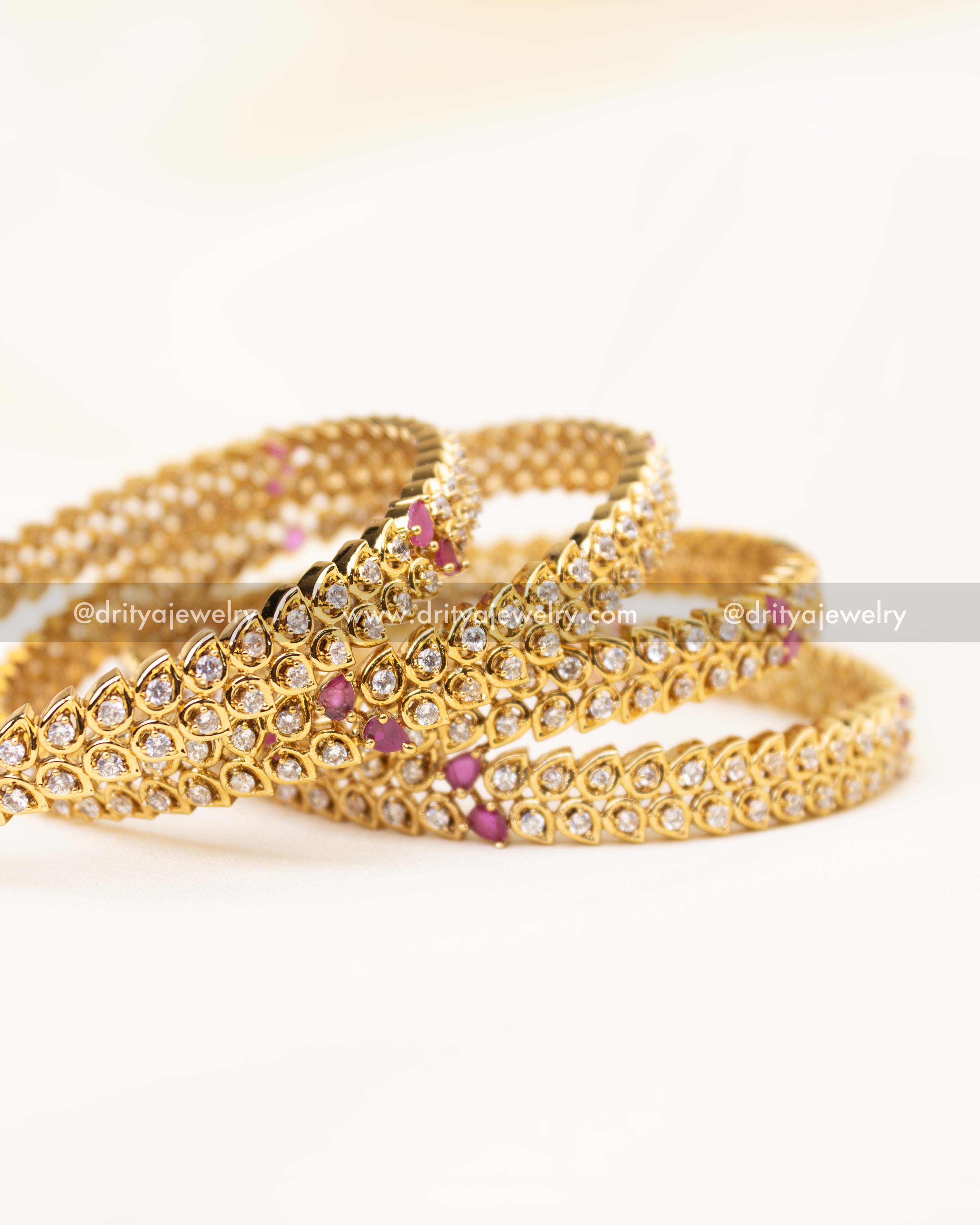 Elegant CZ bangles arranged in a stack showing sparkle and intricate pink detailing.