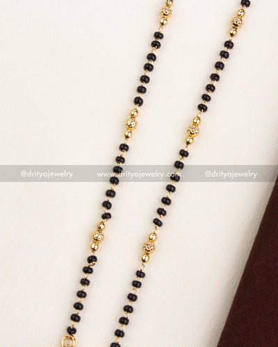 Close-up of double-line black beads with gold-toned textured balls on temple necklace.
