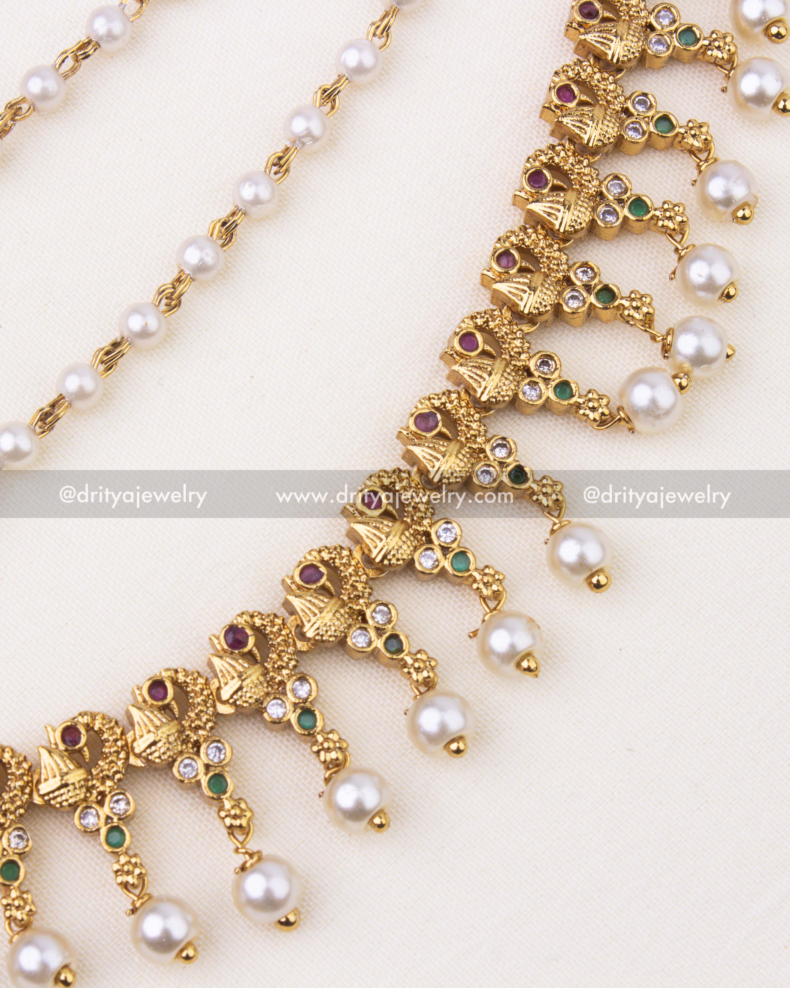 Detailed floral motifs with ruby, green, and CZ stones finished with pearl hangings.