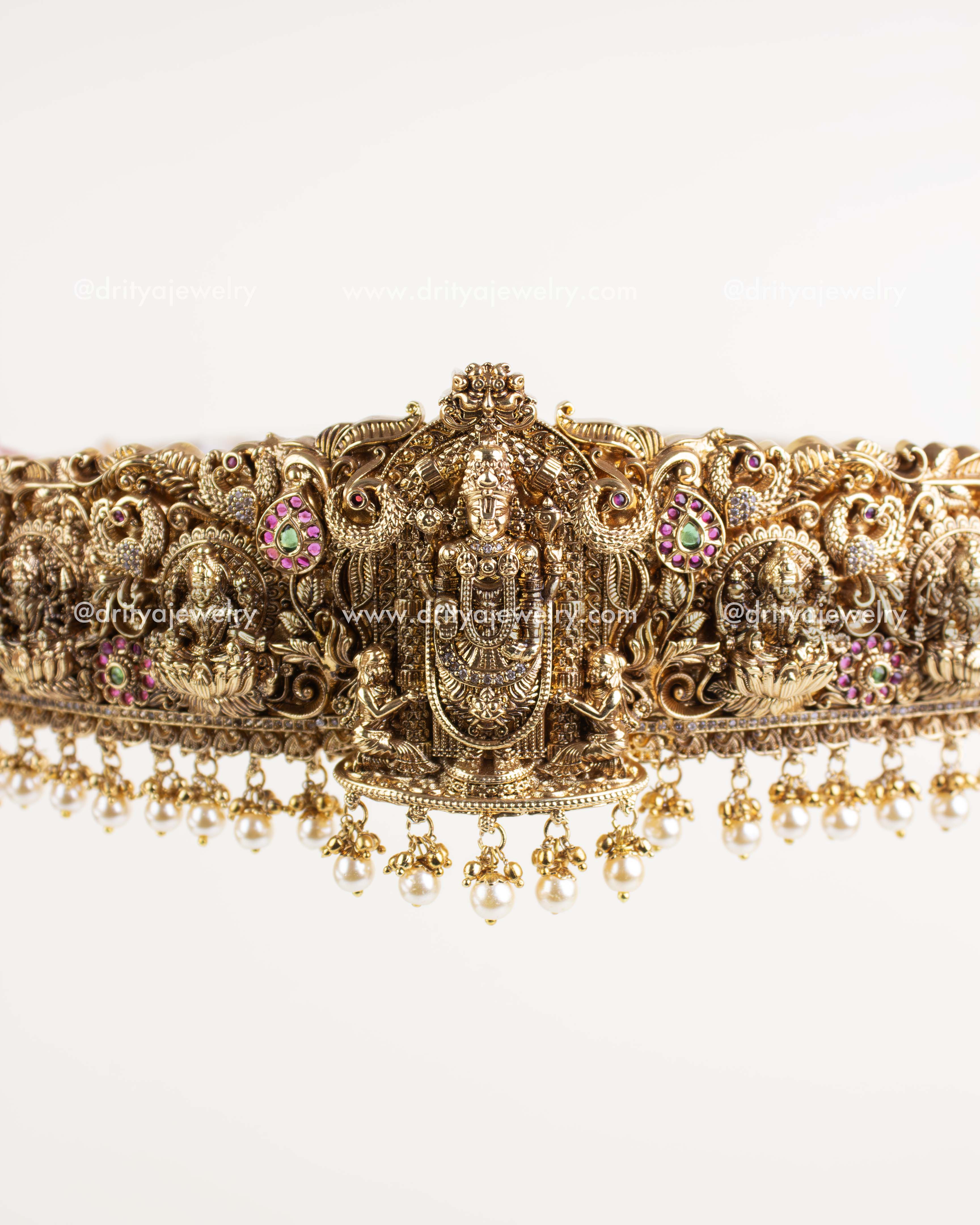 "Intricate Lord Venkateshwara carving with pink, green, and white stones in Nakshi style.