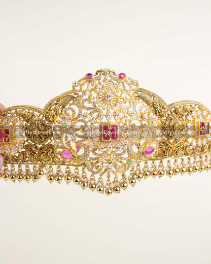 Gold-plated bridal waist belt featuring nakshi detailing, CZ stones, and ruby-green accents.