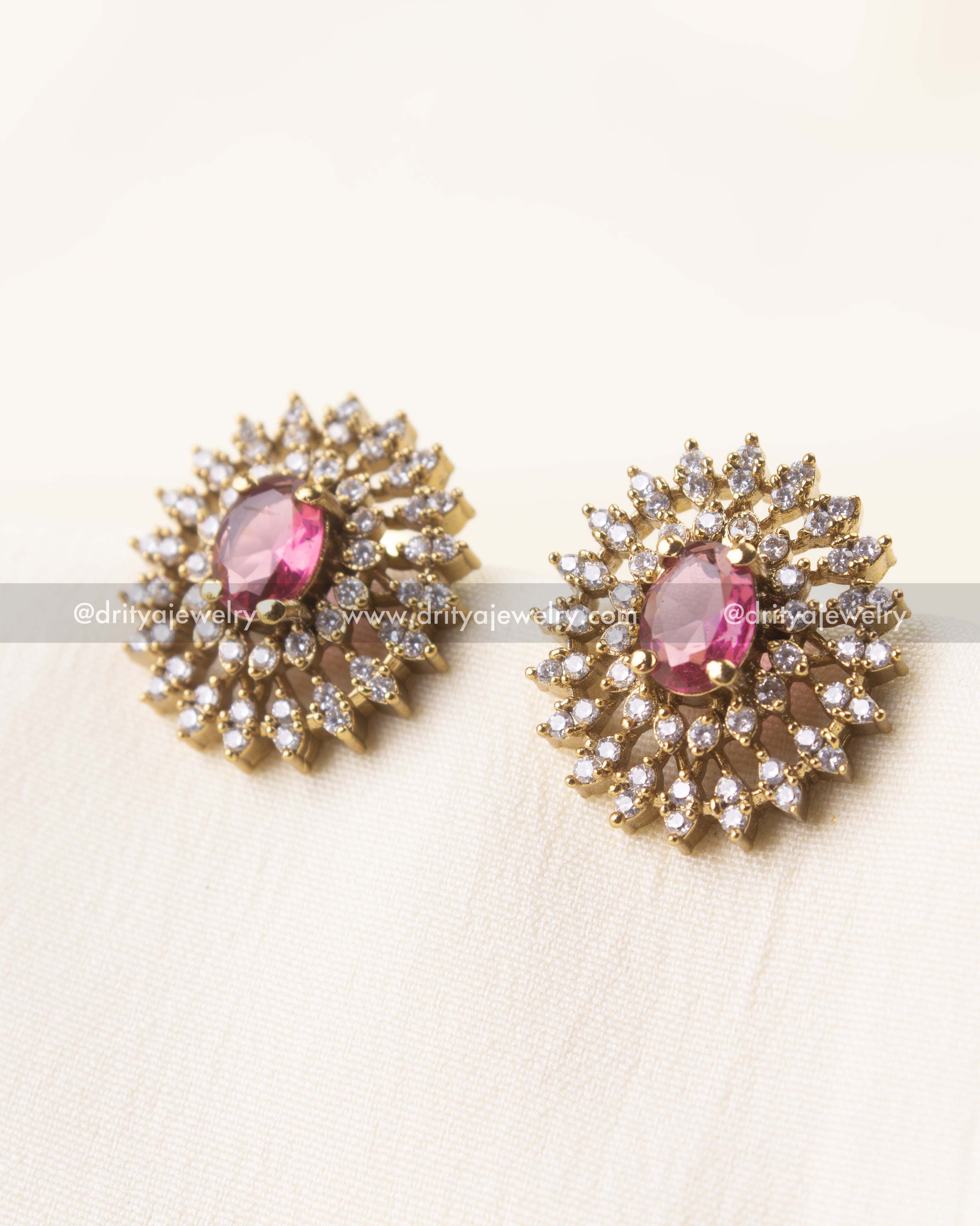 Detailed view of round stud earrings featuring a pink gemstone and CZ-studded petals.