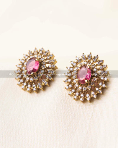 Detailed view of round stud earrings featuring a pink gemstone and CZ-studded petals.