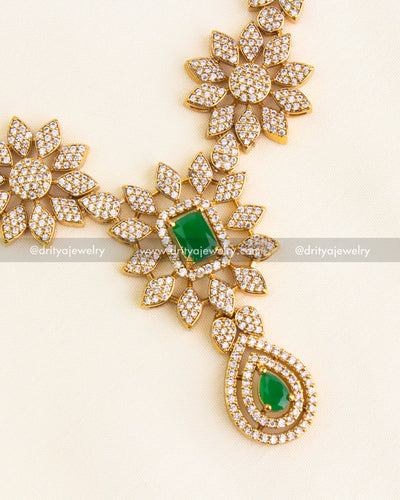 Detailed view of floral necklace pendant with emerald green center and CZ sparkle.