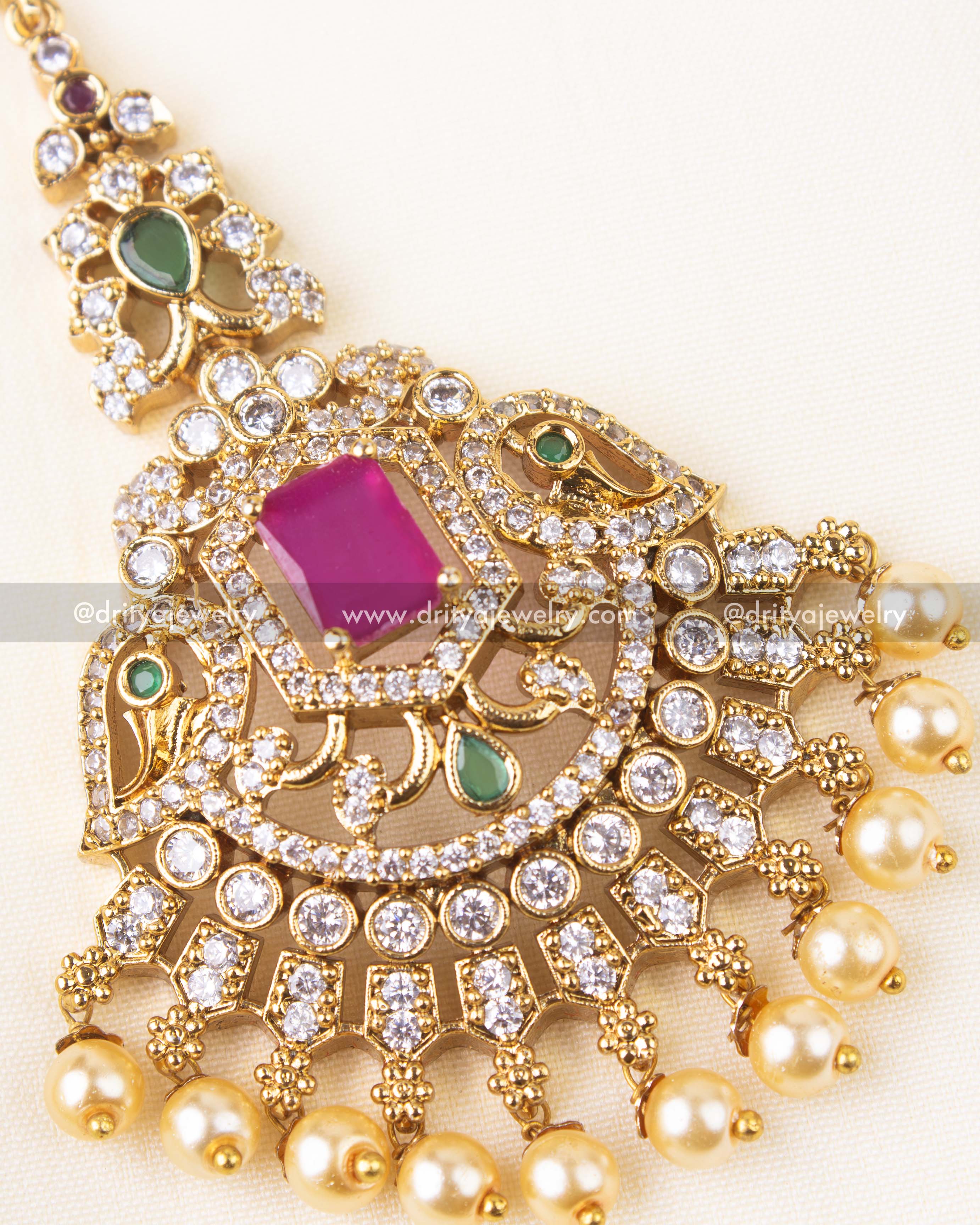 Detailed view of gold Maang Tikka with pink gemstone, floral motifs, and pearl accents