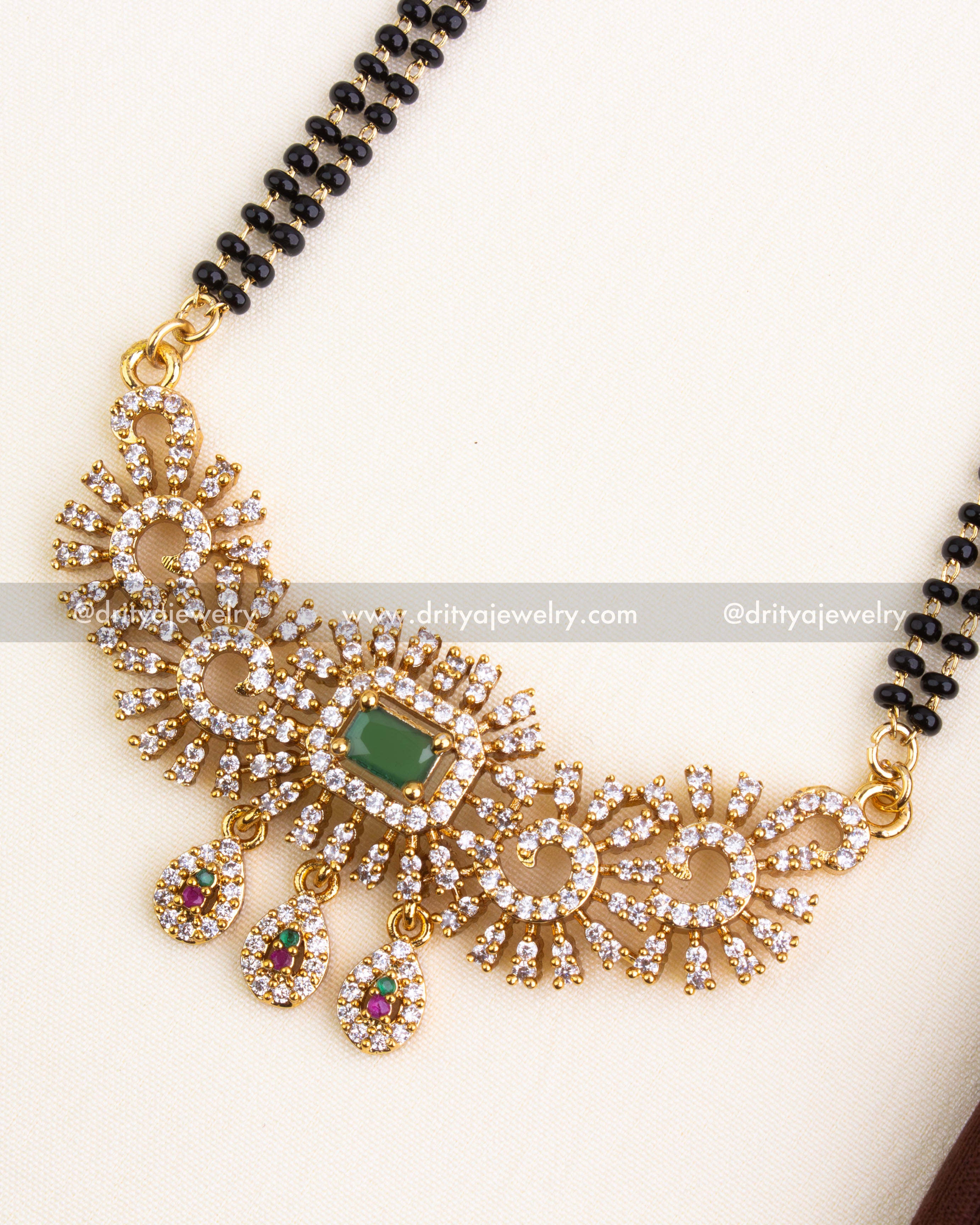Detailed pendant with swirled CZ patterns, green stone, and multicolor teardrop danglers