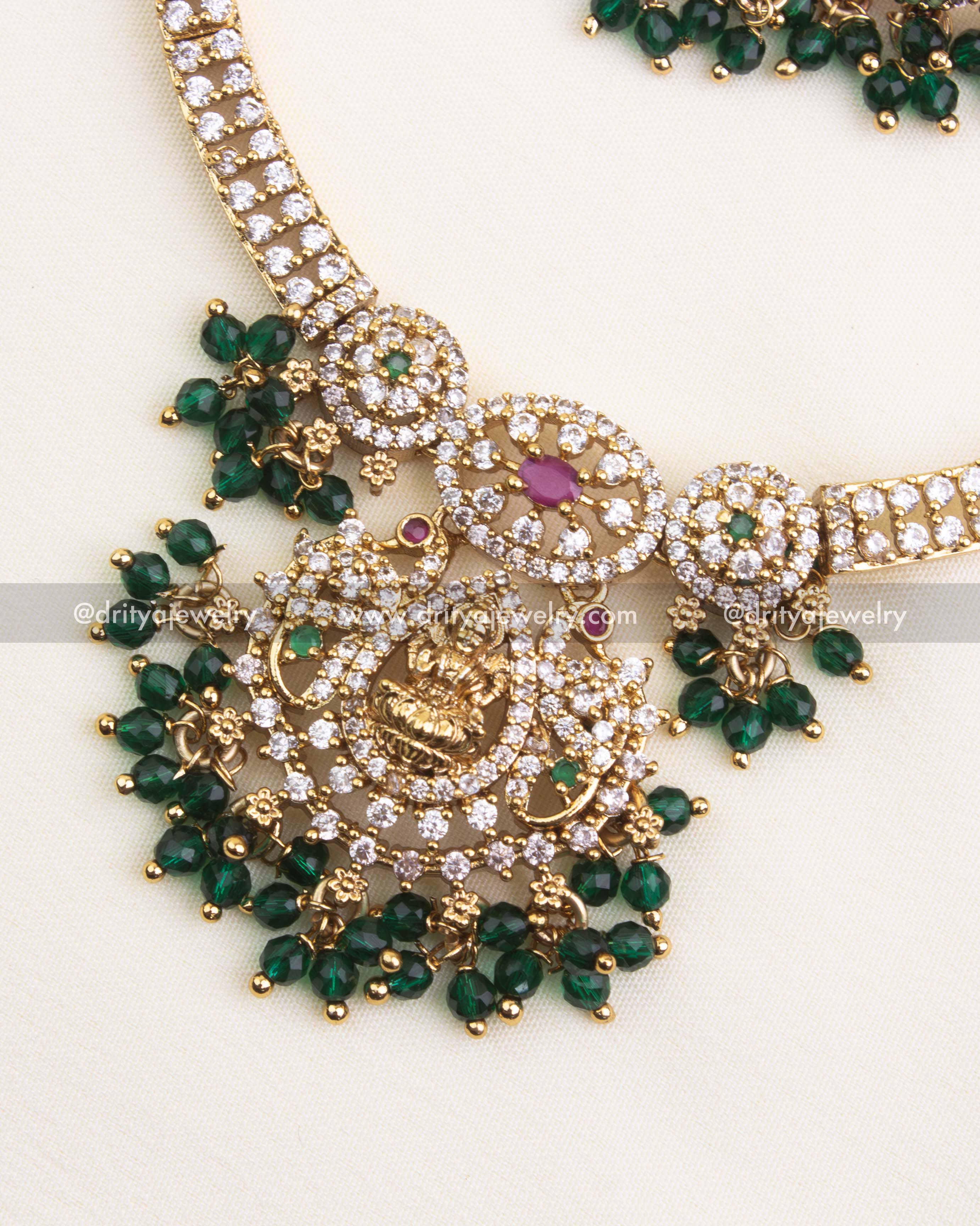 Detailed view of Lakshmi pendant with CZ stones, ruby and emerald highlights, and bead clusters.