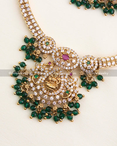 Detailed view of Lakshmi pendant with CZ stones, ruby and emerald highlights, and bead clusters.