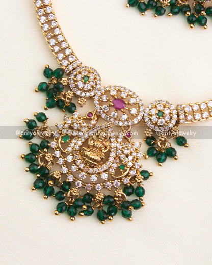 Detailed view of Lakshmi pendant with CZ stones, ruby and emerald highlights, and bead clusters.