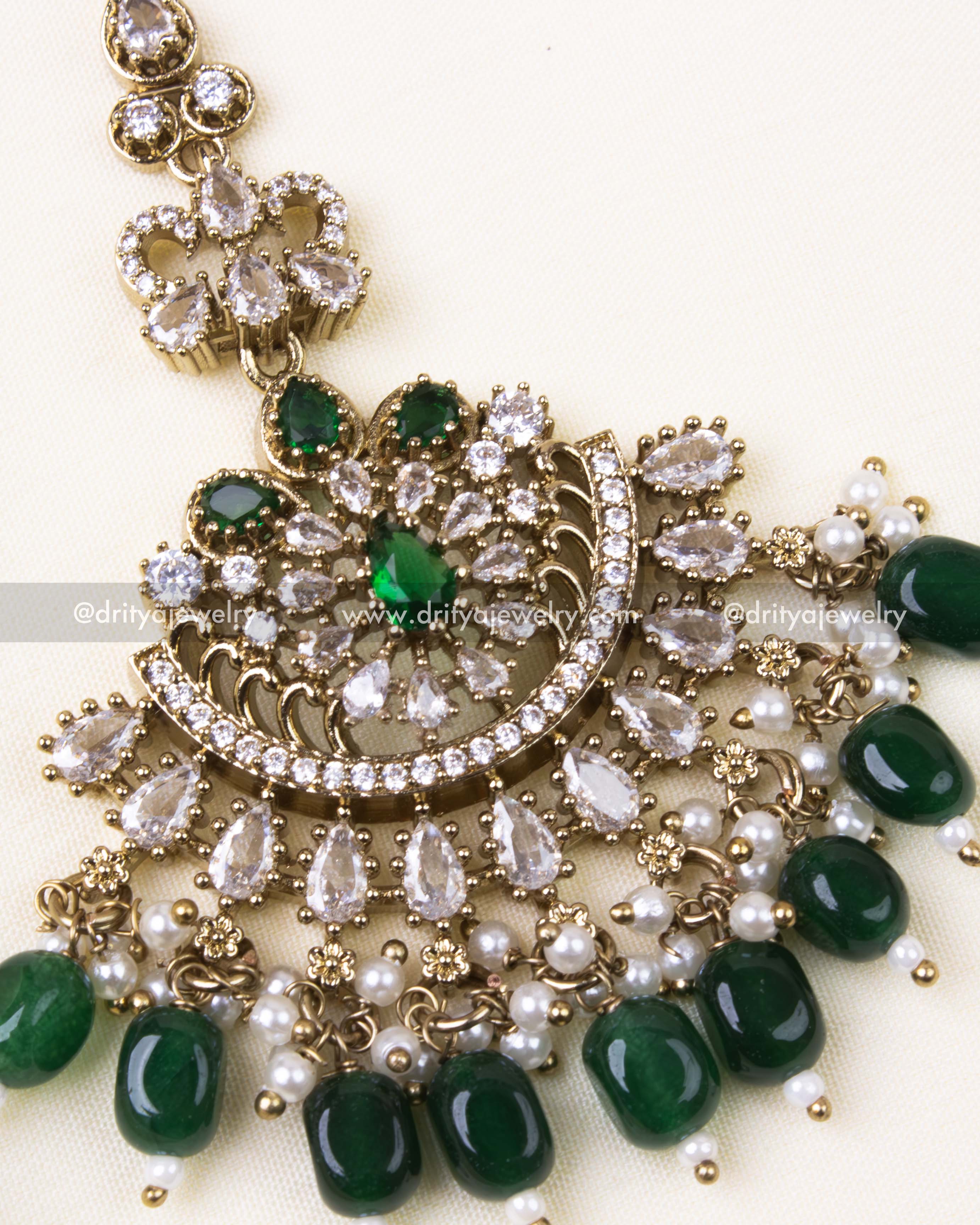 Detailed maang tikka design with emerald green beads and gold antique finish.
