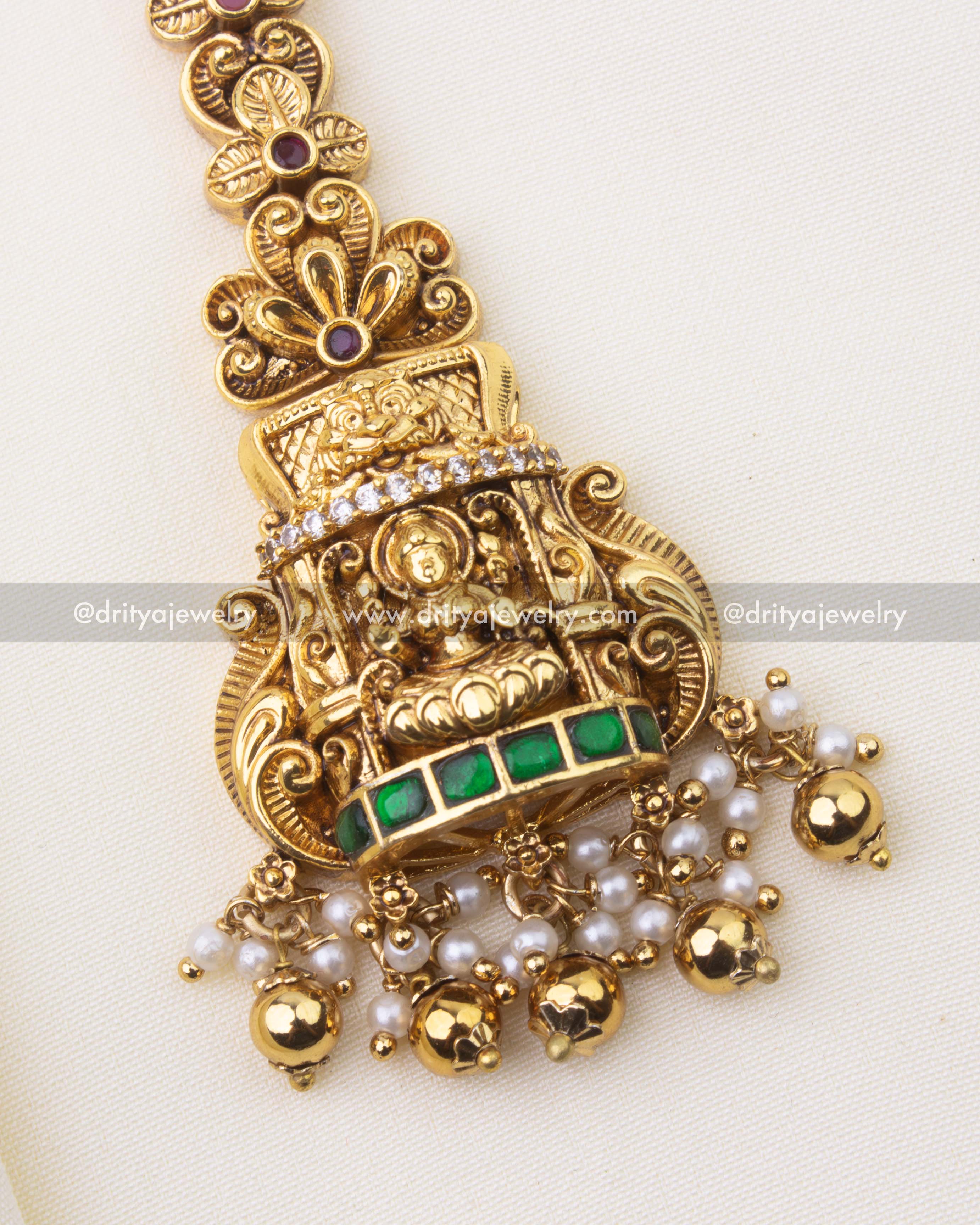 Antique gold-polished temple jewelry Maang Tikka with emerald stones and intricate nakshi design.