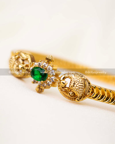 Detailed view of emerald CZ centerpiece with antique gold peacock carvings.