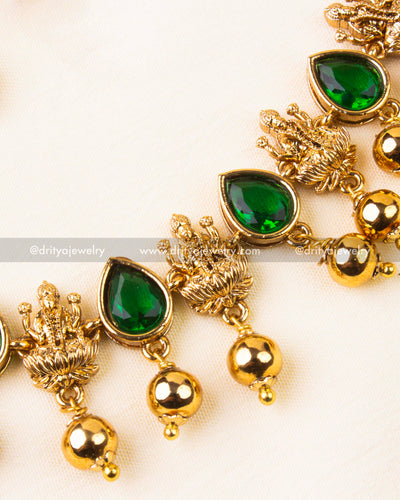 Detailed view of emerald green temple necklace with goddess motifs and gold ball accents.