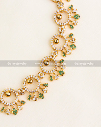 Detailed view of green gemstone and CZ-studded necklace design with gold finish.