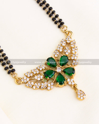 Detailed view of green teardrop stones and CZ-studded floral motif in gold setting.