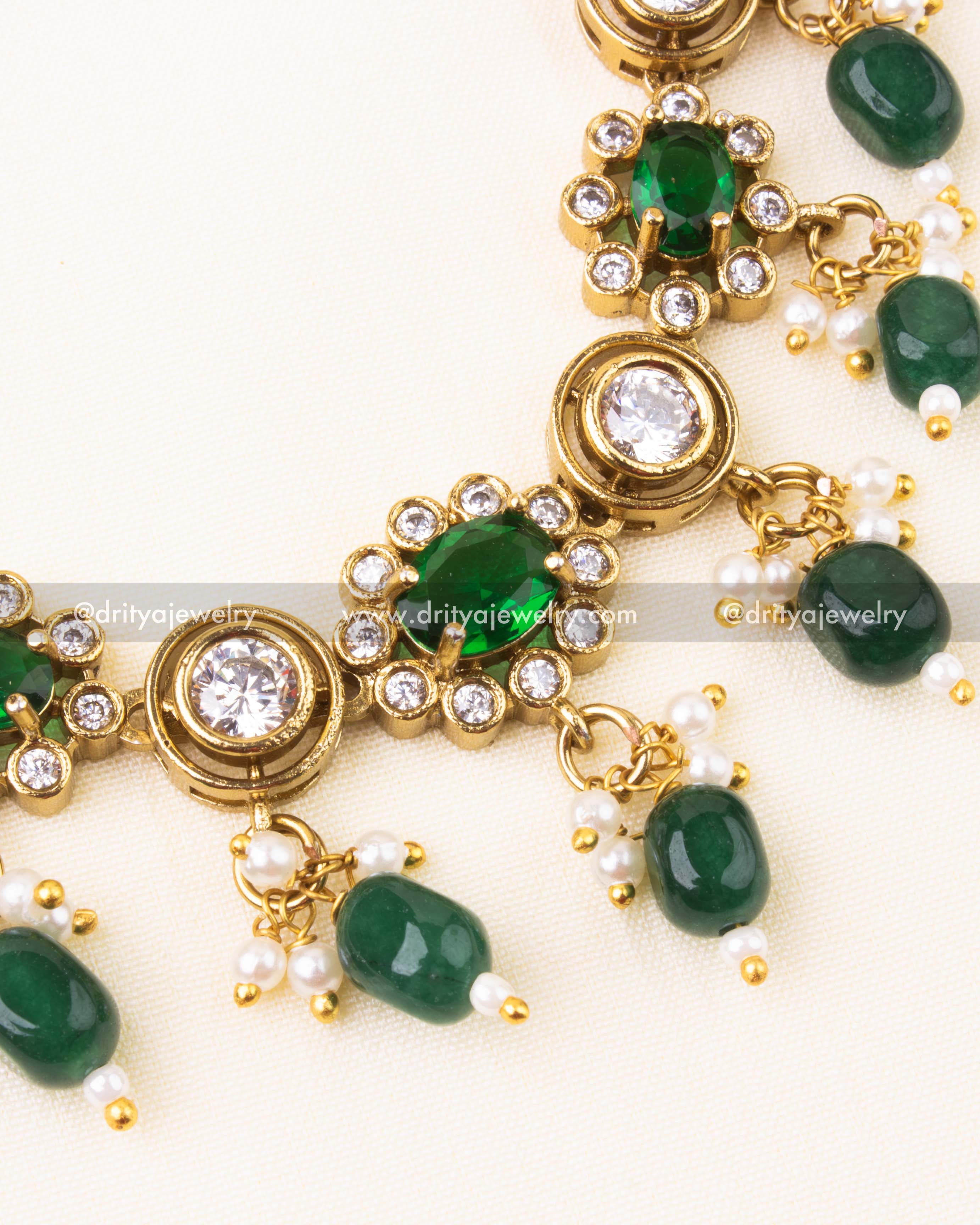 Detailed shot of emerald green stones and pearl bead drops with AD accents.