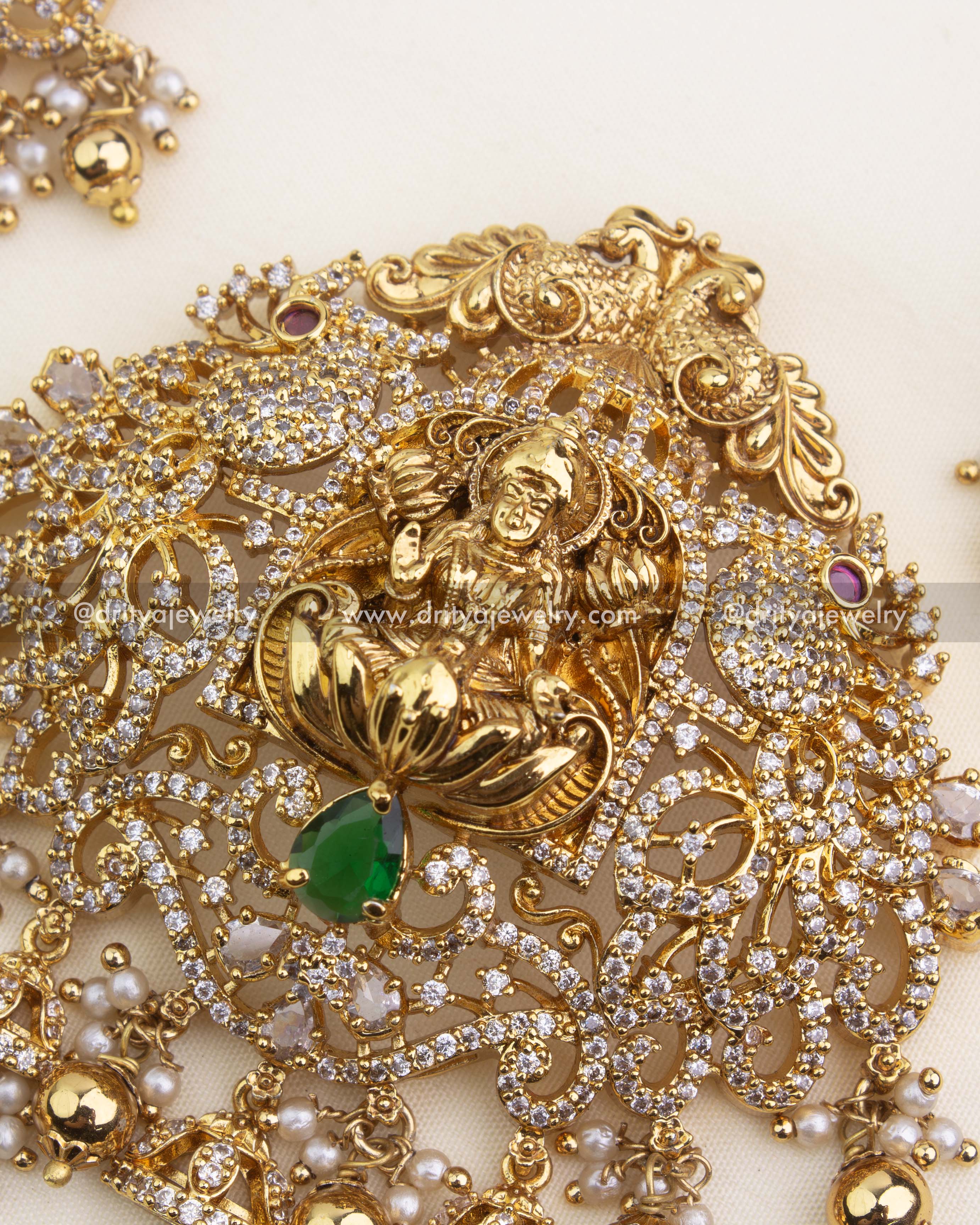 Intricate Lakshmi pendant with CZ detailing, emerald green center stone, and pearl clusters.