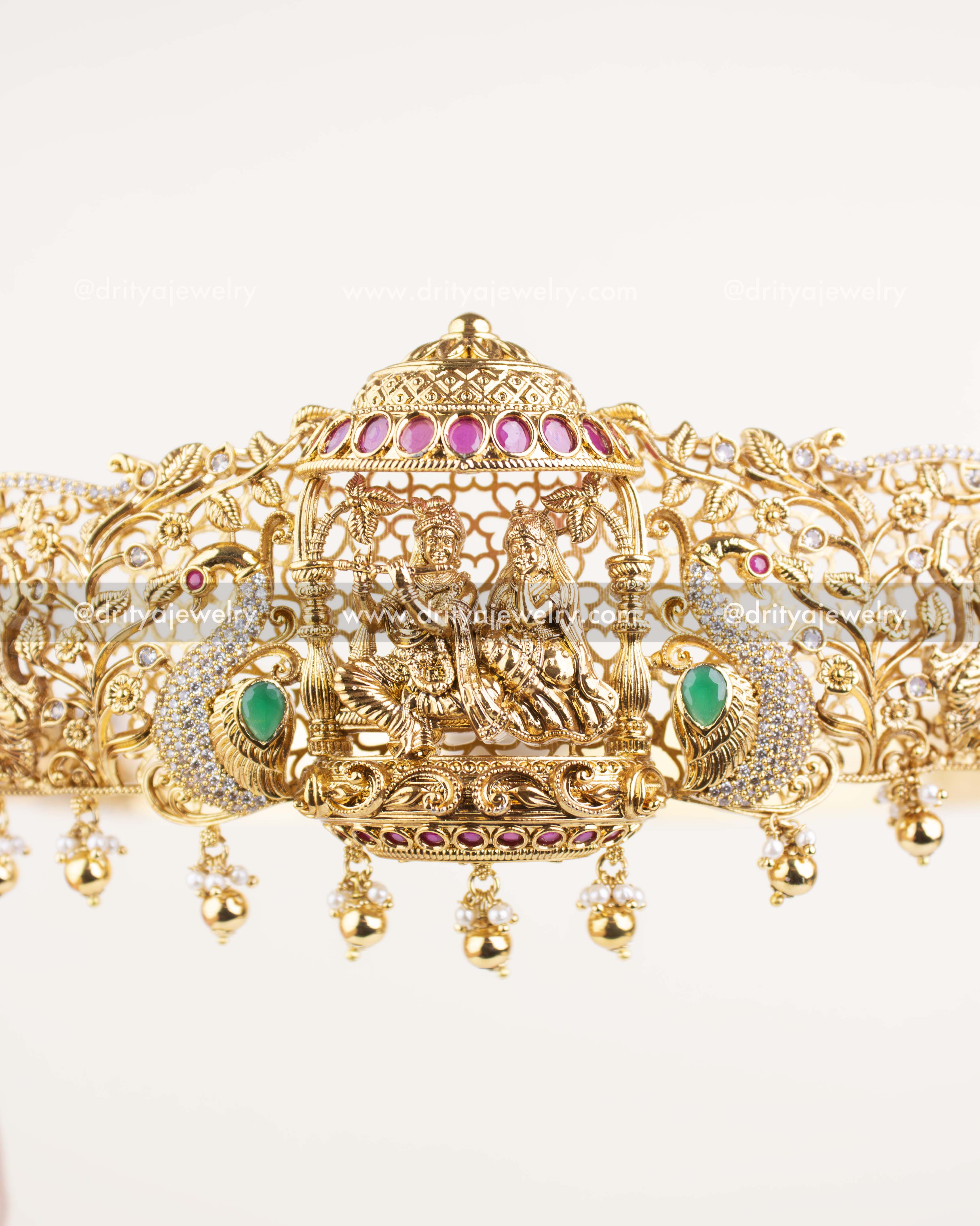 Detailed view of Krishna with flute under pink-studded canopy and gold filigree frame.