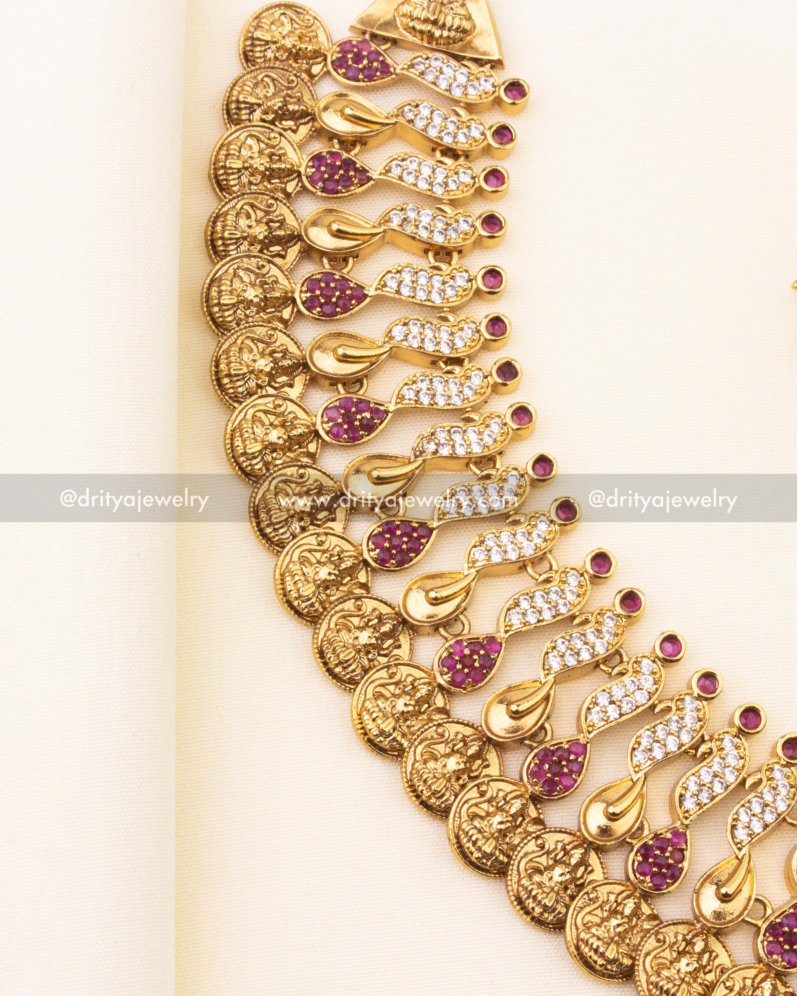 Detailed view of Kasulu necklace with ruby and CZ paisley motifs and Lakshmi coin engravings.