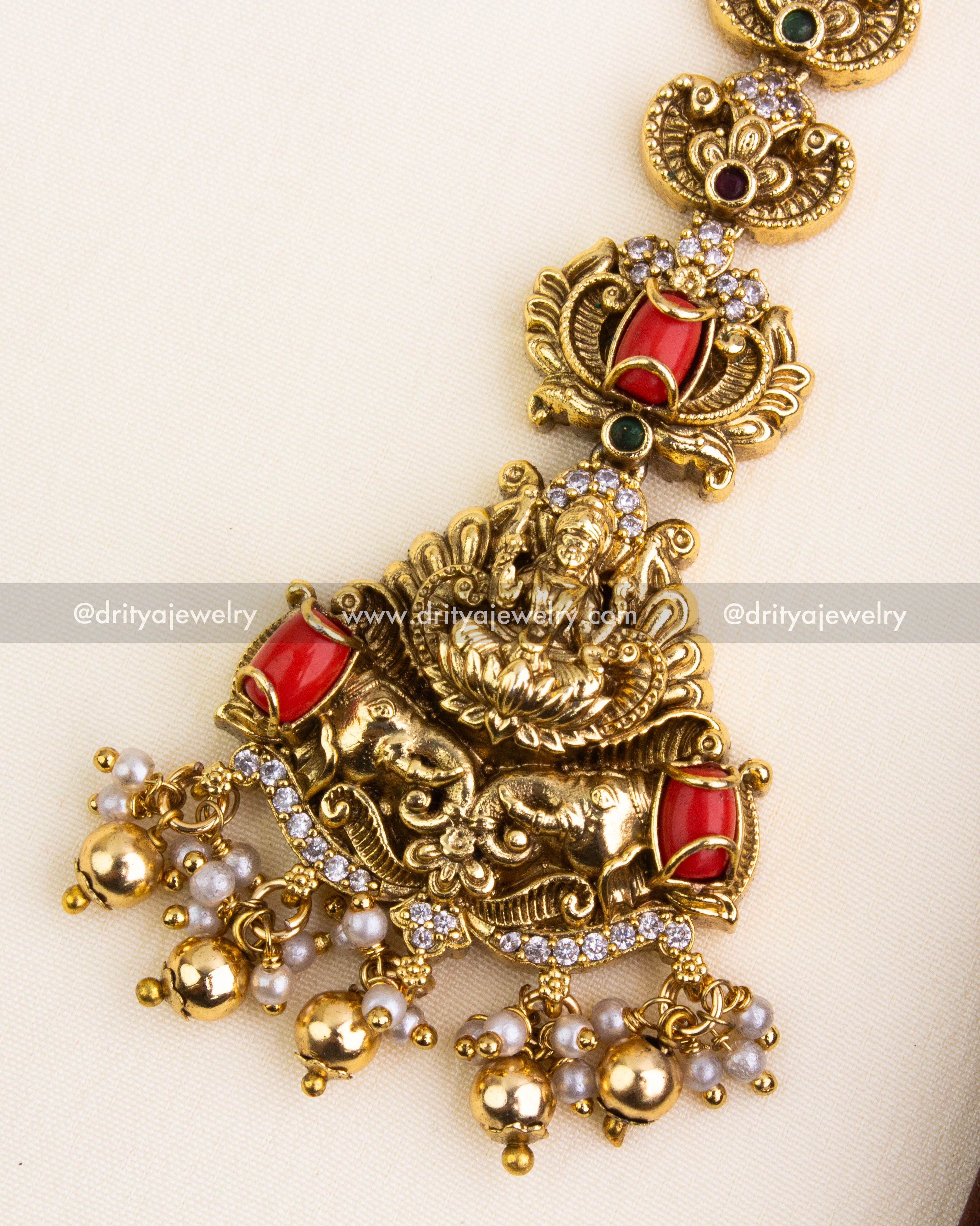Detailed view of coral-accented maang tikka with Lakshmi centerpiece, CZ stones, and golden bead danglers.