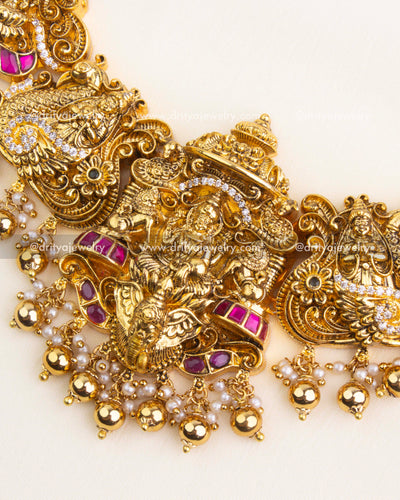Detailed Lakshmi motif in temple jewelry with kemp stones and hanging pearls.