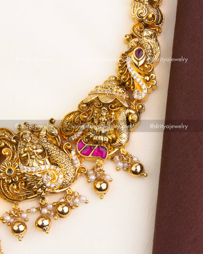 Detailed Lakshmi motif in temple jewelry with kemp stones and hanging pearls.