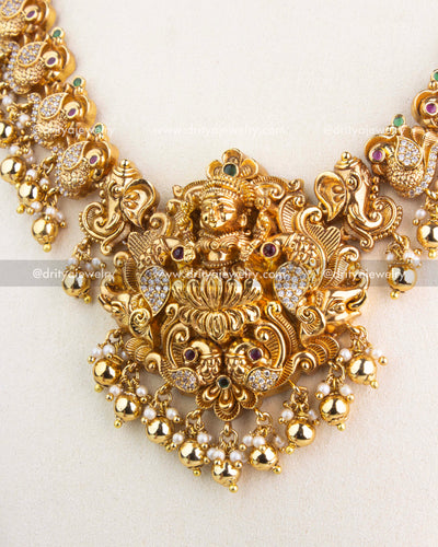 Intricately carved Lakshmi pendant with peacock designs, CZ accents, and pearl-gold hangings.