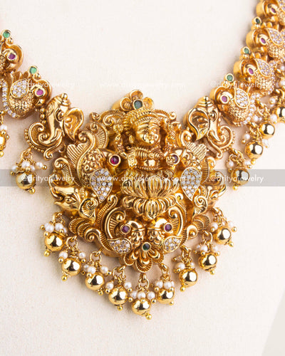 Intricately carved Lakshmi pendant with peacock designs, CZ accents, and pearl-gold hangings.