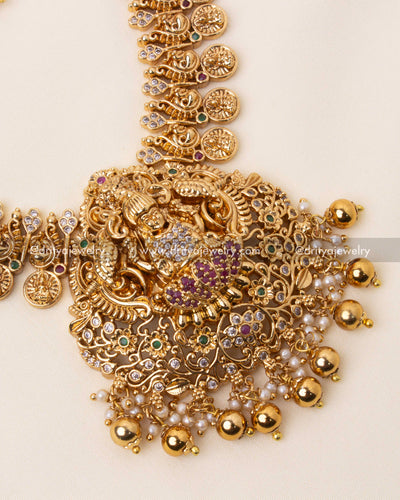 Detailed view of a temple-inspired Lakshmi Devi pendant with antique gold plating, pearl embellishments, and red stones.