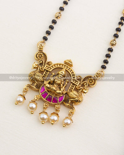 Detailed Lakshmi temple pendant with pink kemp accents, black bead chain, and pearl drop hangings.
