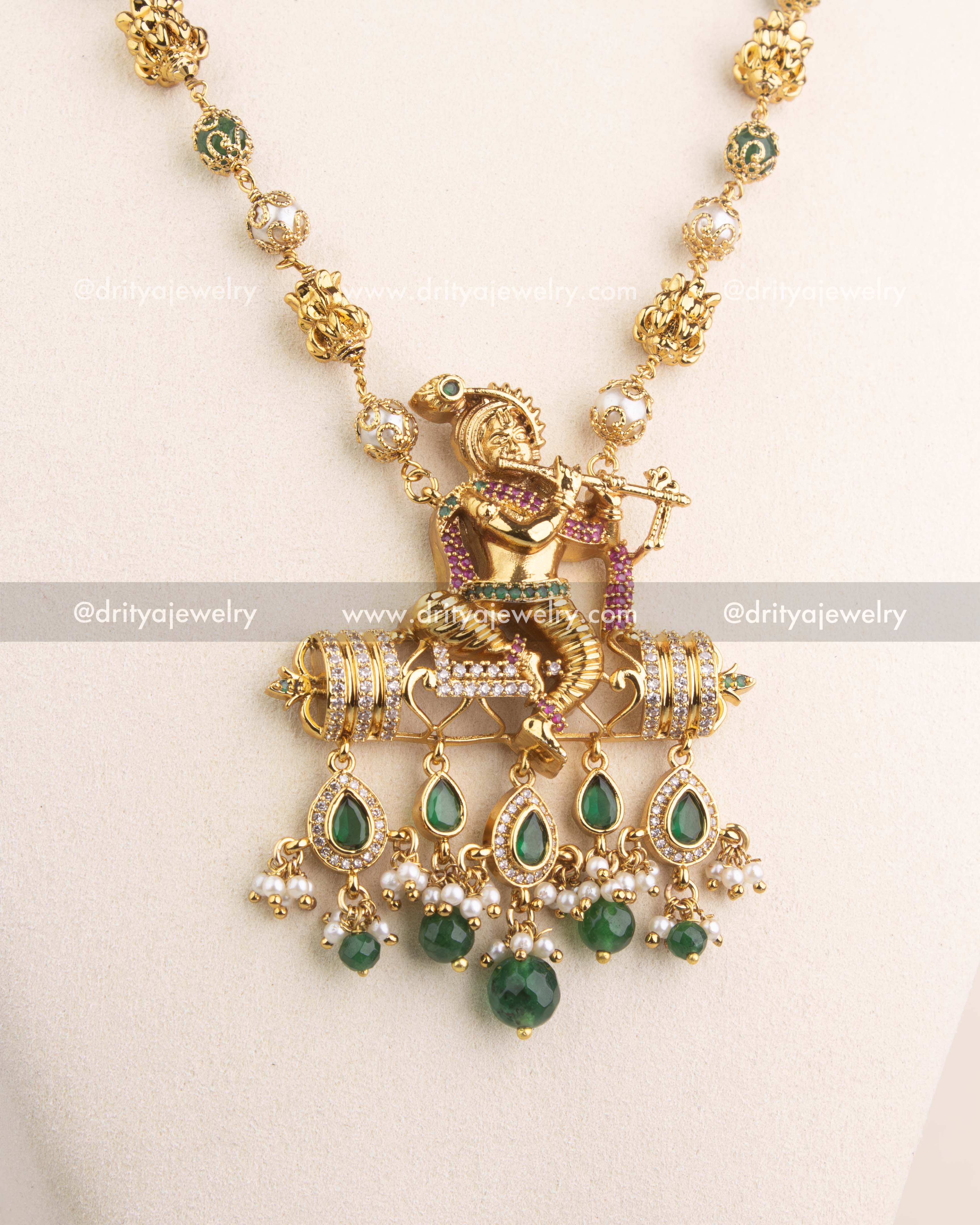Intricate temple jewelry pendant featuring Lord Krishna with CZ stones and green bead drops.