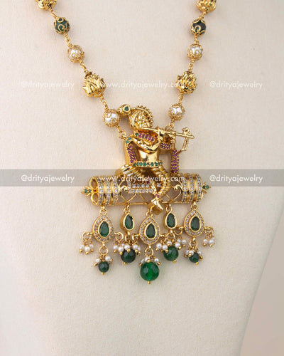 Intricate temple jewelry pendant featuring Lord Krishna with CZ stones and green bead drops.