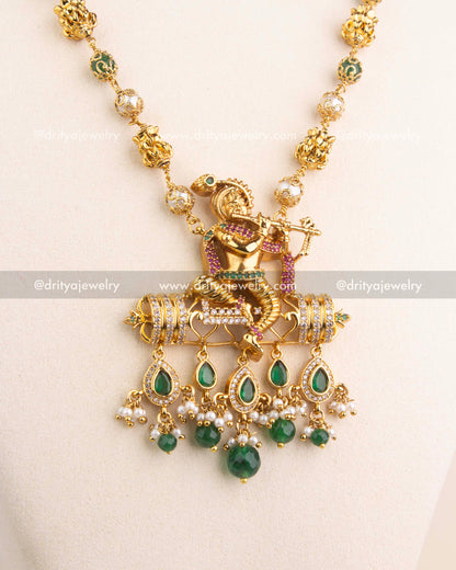 Intricate temple jewelry pendant featuring Lord Krishna with CZ stones and green bead drops.