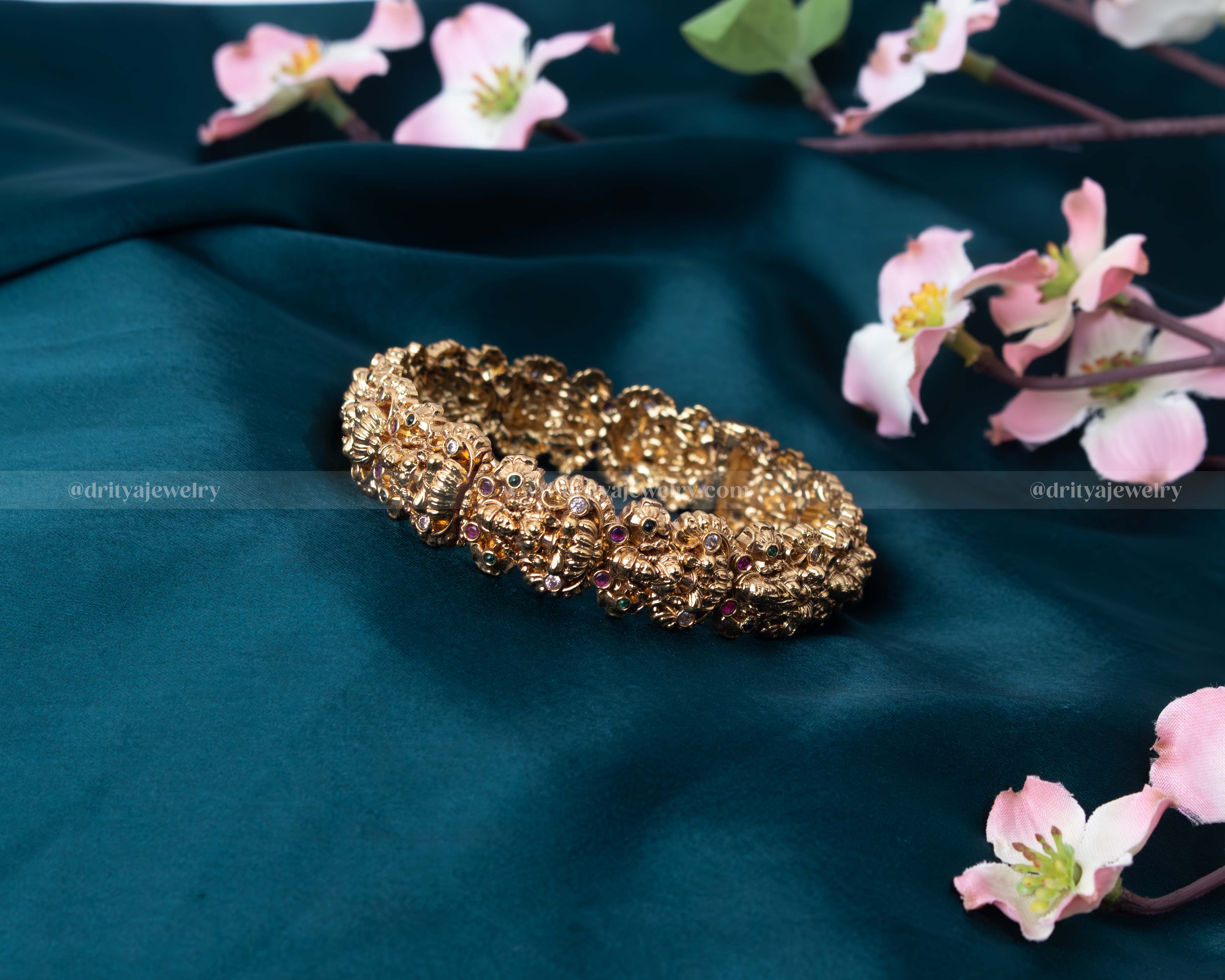 A detailed close-up of the Maha Lakshmi Temple Bangle illustrating the intricate carvings and colorful gemstone embellishments.