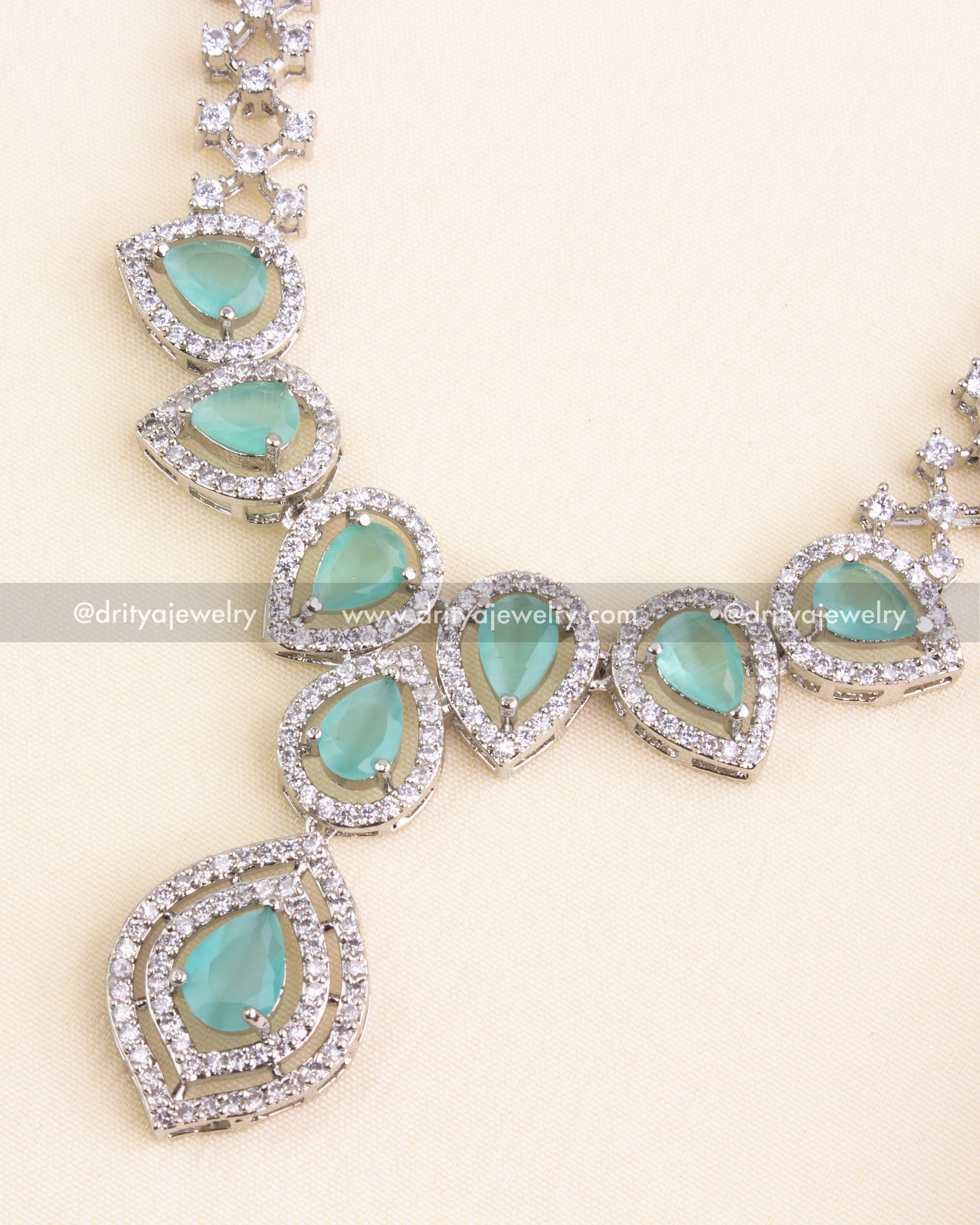 Detailed view of teardrop mint green stones framed with American Diamonds